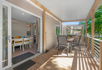 Veranda van Mobile home Porec met eettafel bij Camping Bijela Uvala Kroatië, omringd door bomen.