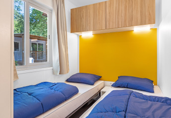 Dormitorio en Mobile home Porec con dos camas individuales, ropa de cama azul y pared amarilla en la Bijela Uvala.