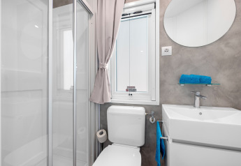 Badkamer in Mobile home Porec op Camping Bijela Uvala, Kroatië met douche, toilet en lavabo.