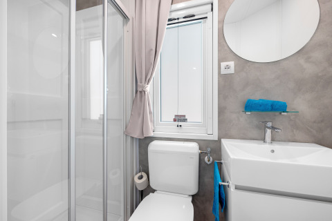Modernes Bad im Mobile Home Porec, Camping Bijela Uvala, Kroatien, mit Dusche, WC und Waschbecken.