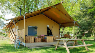 Safaritent Forest Lodge bij Sandberghe in Nederland, met veranda, bankje en picknicktafel in het groen.