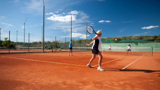 Personas juegan al tenis en una cancha de arcilla en Koversada Camping Resort, Istria, Croacia, bajo el cielo azul.