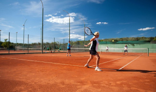 Personas juegan al tenis en una cancha de arcilla en Koversada Camping Resort, Istria, Croacia, bajo el cielo azul.
