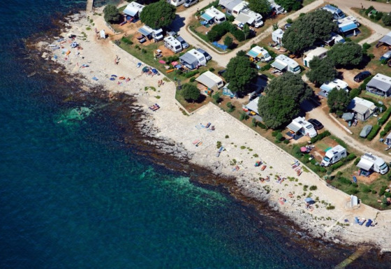 Aerial view of Koversada Camping Resort in Istria, Croatia, featuring campsites along a rocky shoreline.