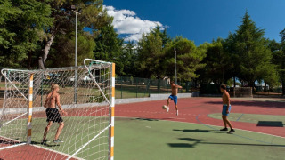Adolescentes juegan fútbol en una cancha exterior rodeada de árboles en el Koversada Camping Resort, Istria, Croacia.
