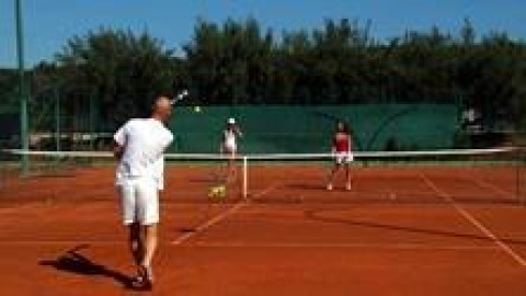 Menschen spielen Tennis auf einem Sandplatz im Koversada Camping Resort, Istrien, Kroatien bei Sonne.