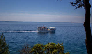 Barco turístico con pasajeros navega cerca de Vrsar, Istria, Croacia, en un mar tranquilo bajo cielo despejado.