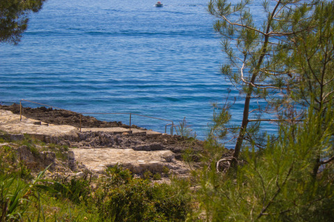 Vista al mar azul en Koversada Camping Resort en Istria, Croacia, con senderos y vegetación natural.