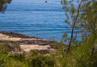 Vista al mar azul en Koversada Camping Resort en Istria, Croacia, con senderos y vegetación natural.