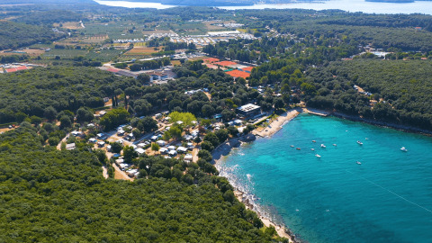 Vista aérea del Camping Porto Sole en Istria, Croacia, rodeado de bosque y con aguas turquesas al frente.