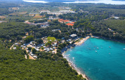 Vista aérea del Camping Porto Sole en Istria, Croacia, rodeado de bosque y con aguas turquesas al frente.
