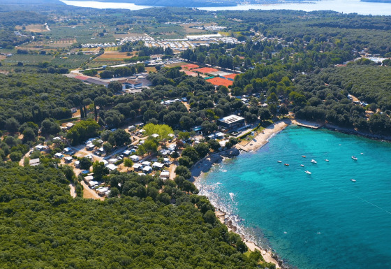 Vue aérienne du Camping Porto Sole en Istrie, Croatie, entouré de forêt et avec une mer bleu turquoise.