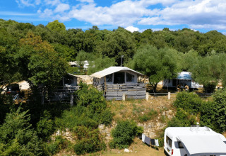 Camping Porto Sole i Istrien, Kroatien, med hytter, campingvogn og frodige træer under en blå himmel.