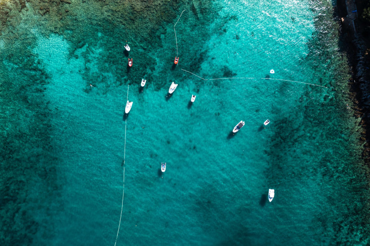 Luftaufnahme von Booten, die im klaren türkisfarbenen Wasser bei Camping Porto Sole, Istrien, Kroatien liegen.