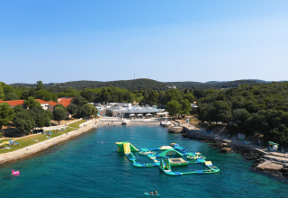 Vista aerea di Camping Porto Sole in Istria, Croazia, con spiaggia, parco acquatico e alberi folti.