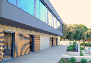 Edificio moderno con doghe in legno e grandi finestre al Camping Porto Sole, villaggio turistico in Istria, Croazia.