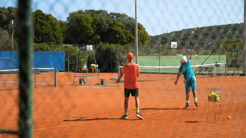 Dos niños juegan al tenis en una pista de arcilla roja en Camping Porto Sole en Istria, Croacia.