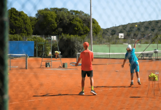 Due bambini giocano a tennis su un campo in terra rossa al Camping Porto Sole in Istria, Croazia.