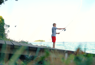 Dreng fisker ved havet ved Camping Porto Sole, en feriepark i Istrien, Kroatien, omgivet af natur.
