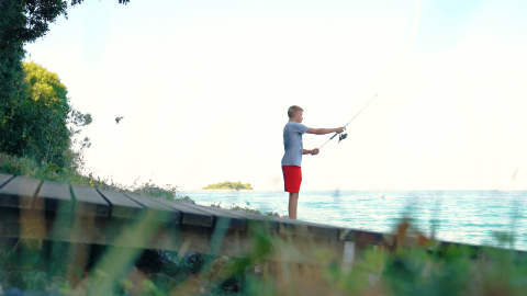 Niño pescando junto al mar en Camping Porto Sole, un parque vacacional en Istria, Croacia, rodeado de naturaleza.