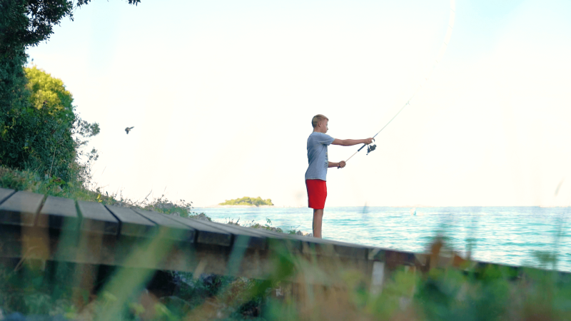 Boy fishing by the sea at Camping Porto Sole, a holiday park in Istria, Croatia, surrounded by nature.