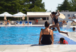 Piscina del camping Porto Sole in Istria, Croazia, con bambini e adulti che giocano e nuotano.