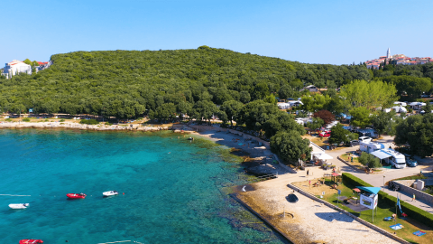 Vista dall’alto di Camping Porto Sole in Istria, Croazia, con mare azzurro, alberi e diverse roulotte sul litorale.