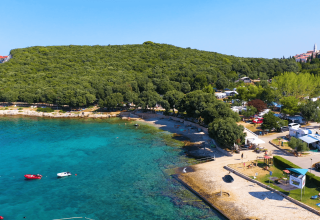 Vista dall’alto di Camping Porto Sole in Istria, Croazia, con mare azzurro, alberi e diverse roulotte sul litorale.