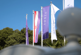 Flag foran grønt løv og blå himmel i Camping Porto Sole, en feriepark i Istrien, Kroatien.
