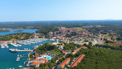 Vista aerea di Camping Porto Sole in Istria, Croazia, con porto turistico, città storica e verde lussureggiante.