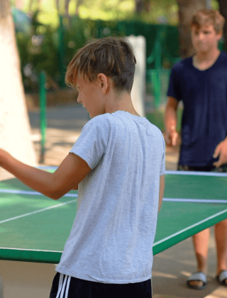 Twee jongens spelen buiten tafeltennis bij Camping Porto Sole, een vakantiepark in Istrië, Kroatië.