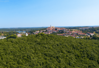 Vista aérea de Camping Porto Sole en Istria, Croacia, con colinas verdes y un pintoresco pueblo al fondo.