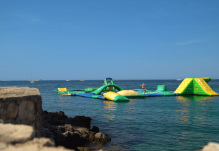 Oppustelig vandforlystelsesbane i havet ved Camping Porto Sole, Istrien, Kroatien under en klar blå himmel.