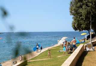 Feriegæster nyder solen og svømmer ved stranden på Camping Porto Sole i Istrien, Kroatien.