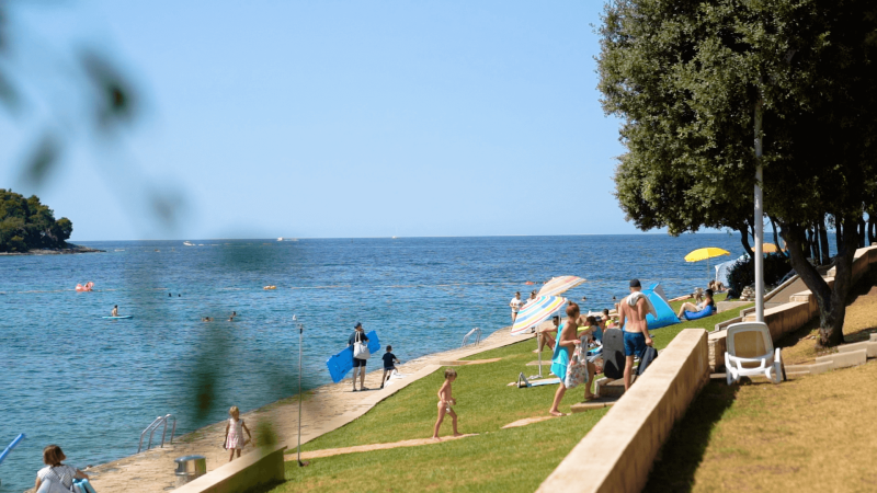 Urlauber entspannen am Strand und schwimmen im Meer im Ferienpark Camping Porto Sole, Istrien.