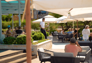 Outdoor seating area at Camping Porto Sole in Istria, Croatia, with guests relaxing under umbrellas.