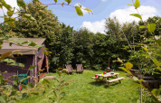 Grüner Garten mit Zelt, Picknicktisch und Liegestühlen im Feather Down Hoeve Zeeland, Niederlande.