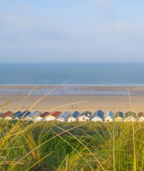 Vista de casetas de playa coloridas junto a la arena cerca de Veere, Zelanda, Países Bajos, con mar al fondo.