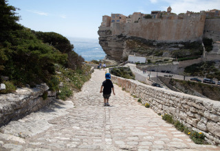 Un enfant marche sur un chemin pavé près de Figari, Corse, France, surplombant la mer et les falaises.