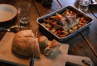 Aftensmad med rustikt brød og ovnbagt kød med rodfrugter på træbord ved Feather Down Figari Corsica.