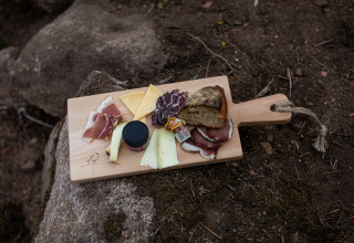 Houten plank met kaas, brood, charcuterie en confituur buiten bij Feather Down Figari Corsica, Frankrijk.