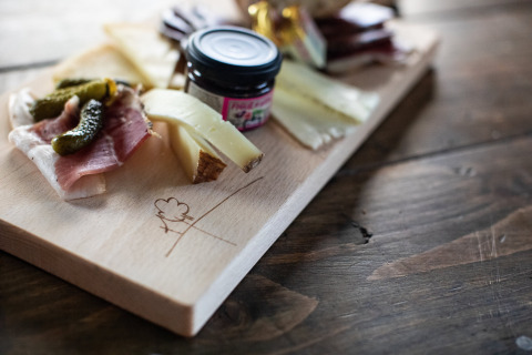 Käse- und Fleischplatte auf Holzbrett mit Essiggurken und Marmelade bei Feather Down Figari Korsika.