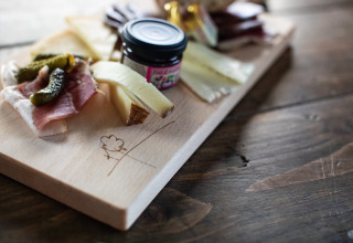 Käse- und Fleischplatte auf Holzbrett mit Essiggurken und Marmelade bei Feather Down Figari Korsika.