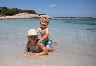 Twee blije kinderen spelen in het ondiepe water van Feather Down Figari Corsica vakantiepark in Frankrijk.