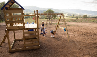 Niños juegan en un parque infantil de madera con columpios en Feather Down Figari Corsica, Francia.
