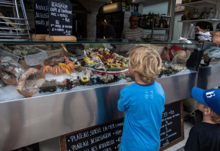 Twee kinderen bewonderen een vitrine vol verse zeevruchten op een marktstand in Corsica, Frankrijk.