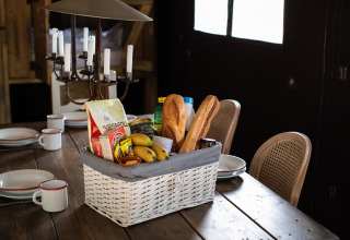 Ein Frühstückskorb mit Baguette, Bananen und Lebensmitteln auf Holztisch im Ferienhaus in Korsika, Frankreich.