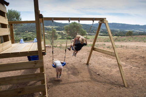 Niños jugando en un columpio en Feather Down Figari Corsica, un parque vacacional en Córcega, Francia.