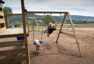 Niños jugando en un columpio en Feather Down Figari Corsica, un parque vacacional en Córcega, Francia.