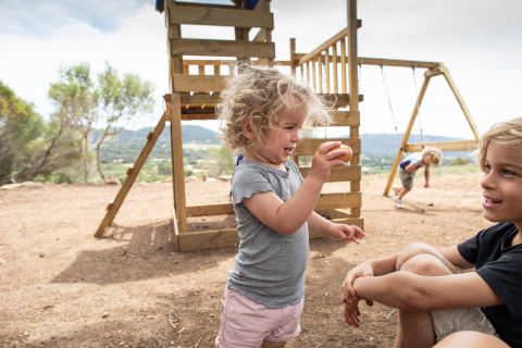 Børn leger ved en legeplads på Feather Down Figari Corsica feriepark i Korsika, Frankrig, på en solrig dag.